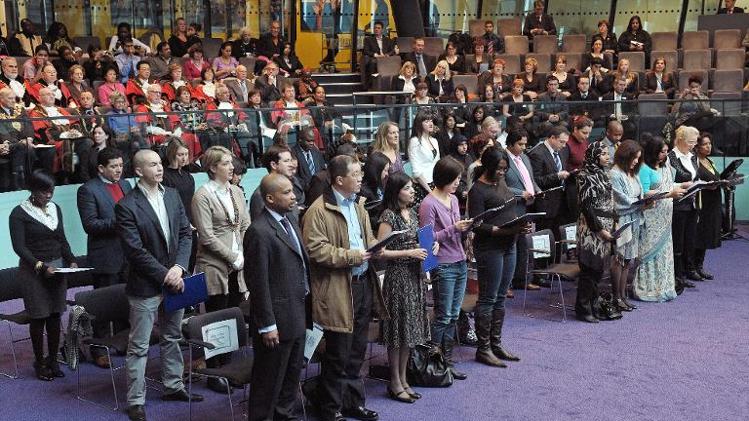 Immigrants to the United Kingdom take an oath before being presented with a certificate of citizenship by the London Mayor Boris Johnson at City Hall, London, on November 20, 2009