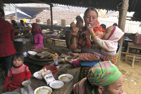 Hai mẹ con người Mông đang cho nhau ăn trong khu ăn uống.