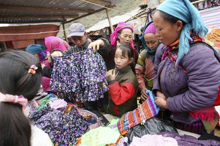 Một người đàn ông đang chọn chiếc váy cho con gái ở khu vực bán quần áo truyền thống.