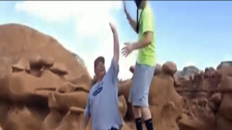 FILE - This file frame grab from a video taken by Dave Hall shows two men cheering after a Boy Scouts leader knocked over an ancient Utah desert rock formation at Goblin Valley State Park. Prosecutors have filed charges Friday Jan. 31, 2014, against two former Boy Scout leaders accused of toppling ancient rock formations at Utah’s Goblin Valley State Park. State Parks officials say Glenn Taylor was charged with criminal mischief. David Hall was charged with aiding criminal mischief, another felony. (AP Photo/Dave Hall, File)