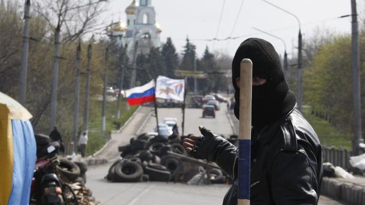 A pro-Russia militiaman guards a barricade bearing the Russian flag on the road leading to the eastern Ukrainian city of Slavyansk on April 14, 2014