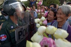 People offer flowers to anti riot-policemen in front of the Ministry of Defence in Phnom Penh on September 6, 2013. Demonstrators on Saturday railed against the hotly contested CPP poll win, aware final results due on Sunday will effectively close the opposition's legal options to appeal.