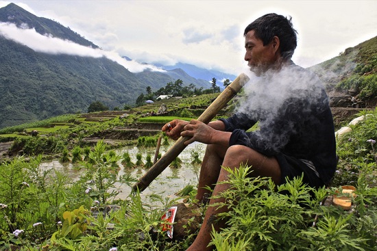 a Black Hmong man takes a break from working in the rice terraces outside of Sapa
